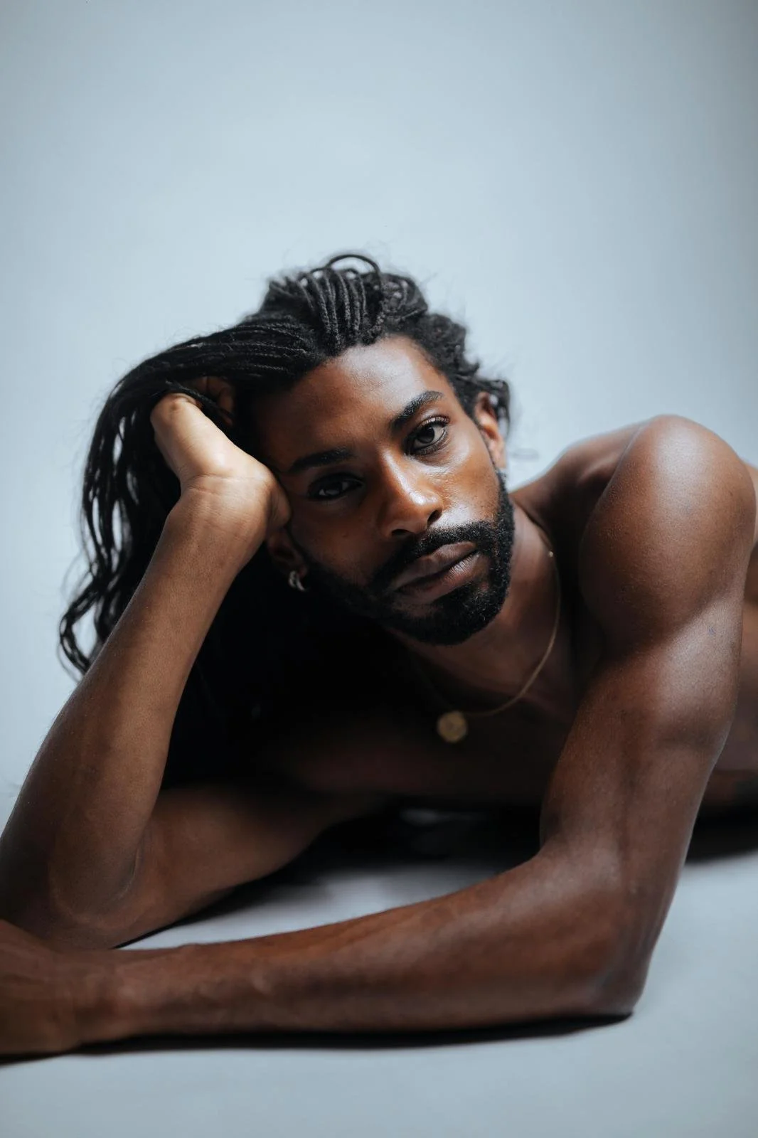 Portrait of Emmanuel Diela Nkita reclining on the floor, resting his head on one hand.