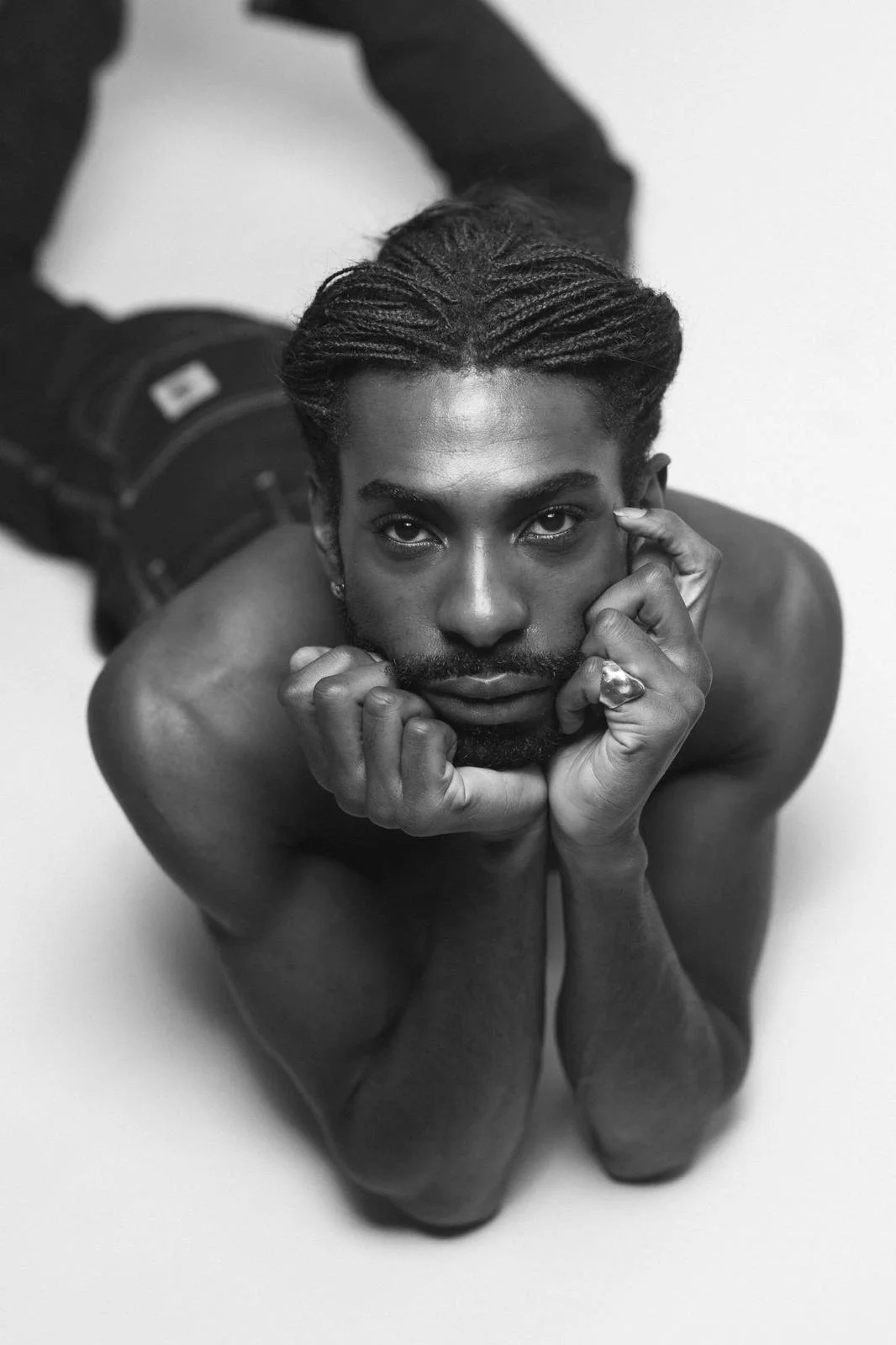 Black-and-white portrait of Emmanuel Diela Nkita resting his face in his hands.
