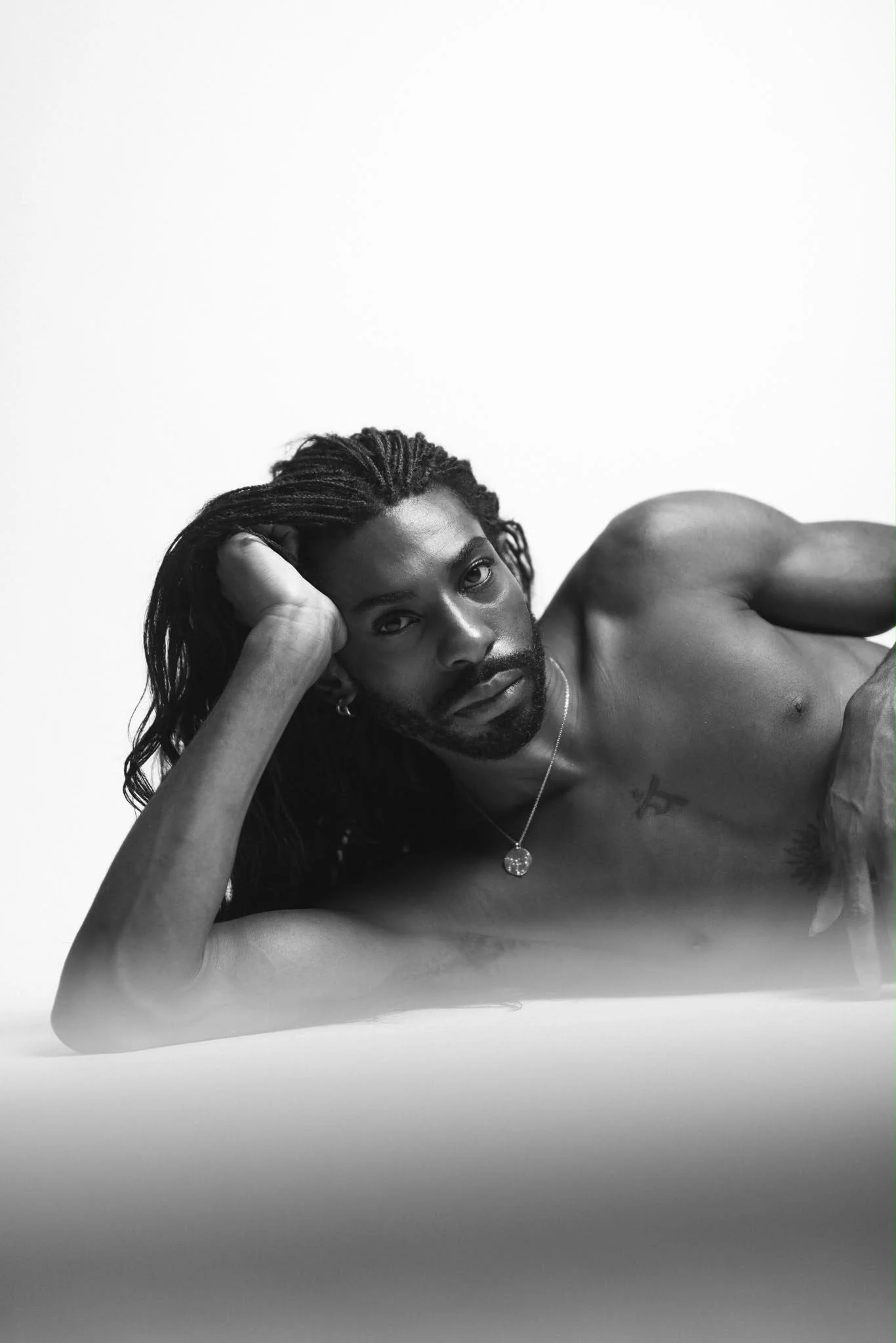 Black-and-white portrait of Emmanuel Diela Nkita reclining on his side.