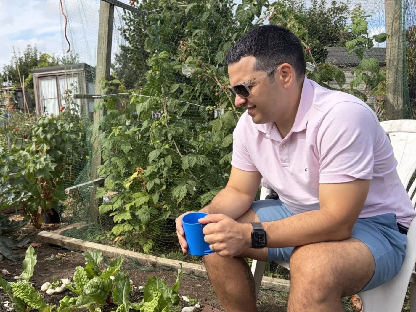 A person sitting in a garden with a cup of tea