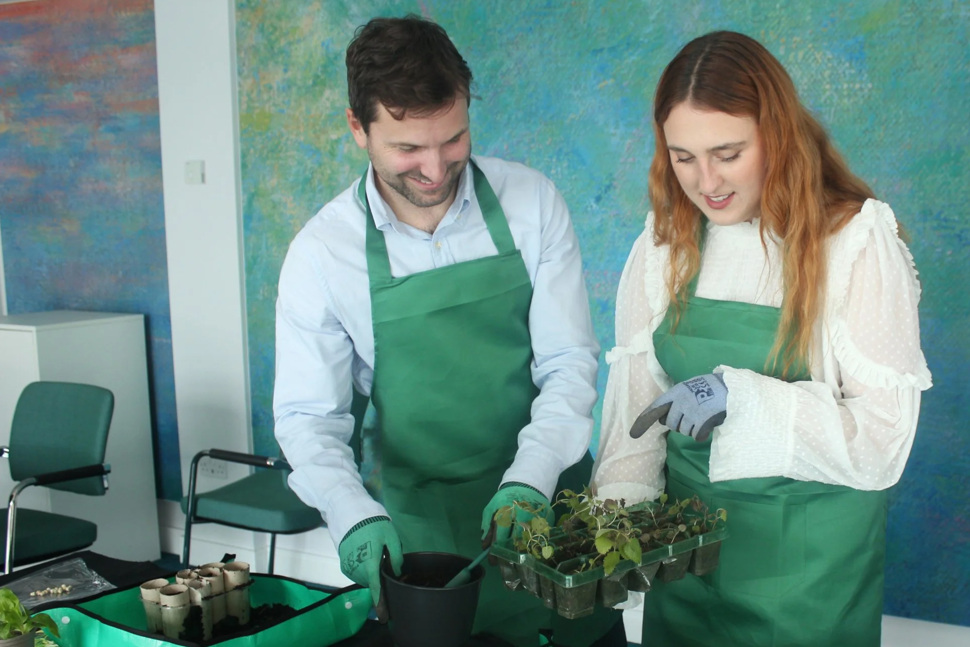 Two smiling people gardening indoors
