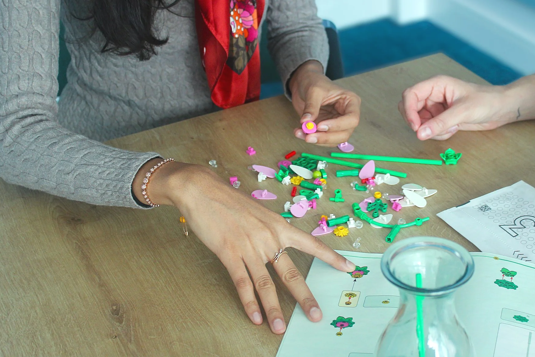 Two people in an office sitting at a table making Lego flowers