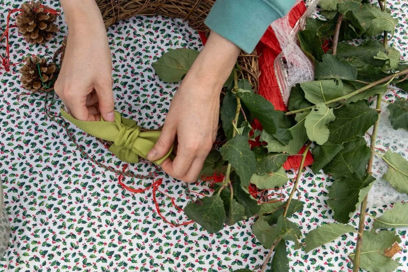 A close up of someone making a festive wreath
