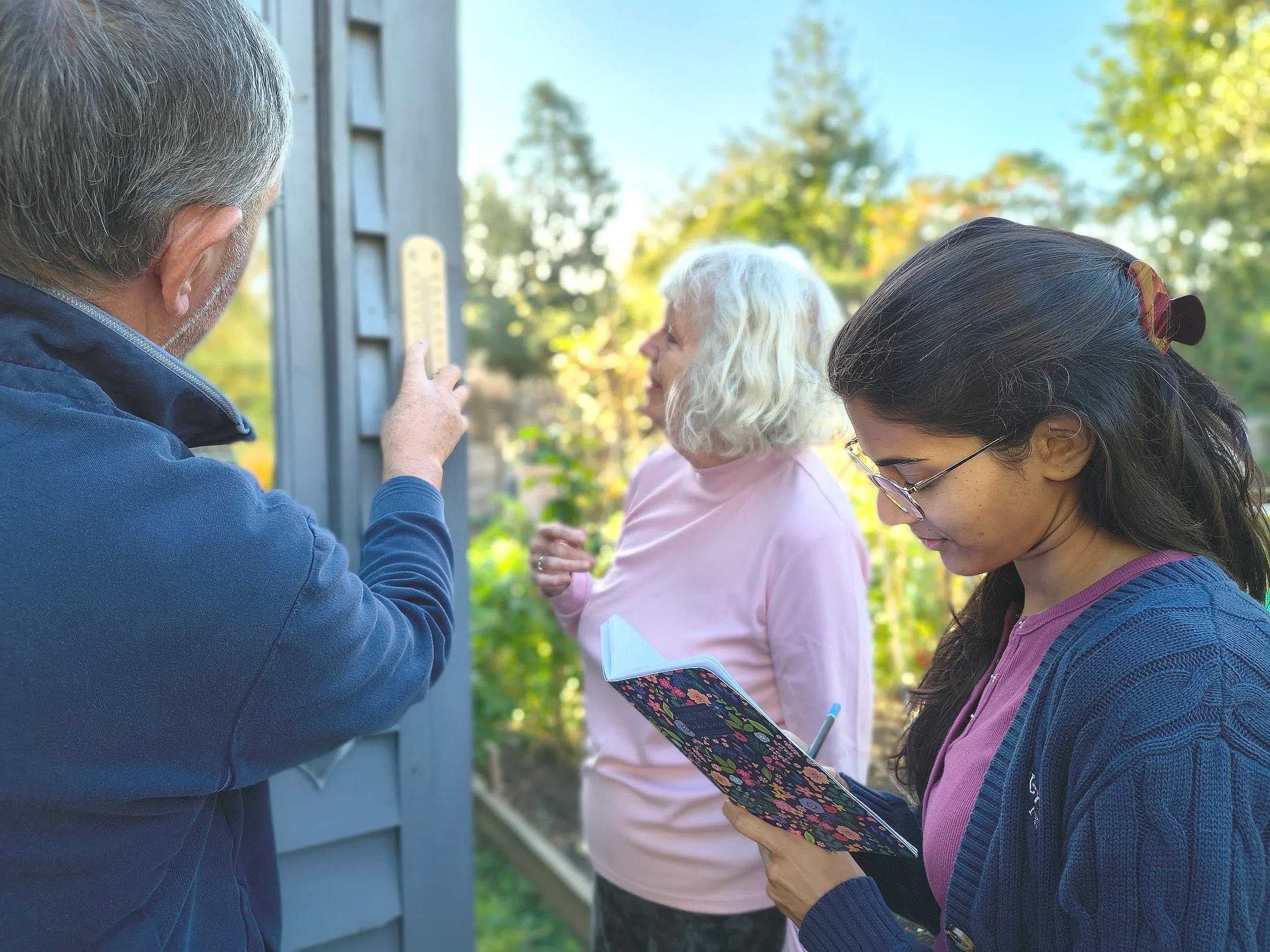 A group of people looking at a thermometer in a garden