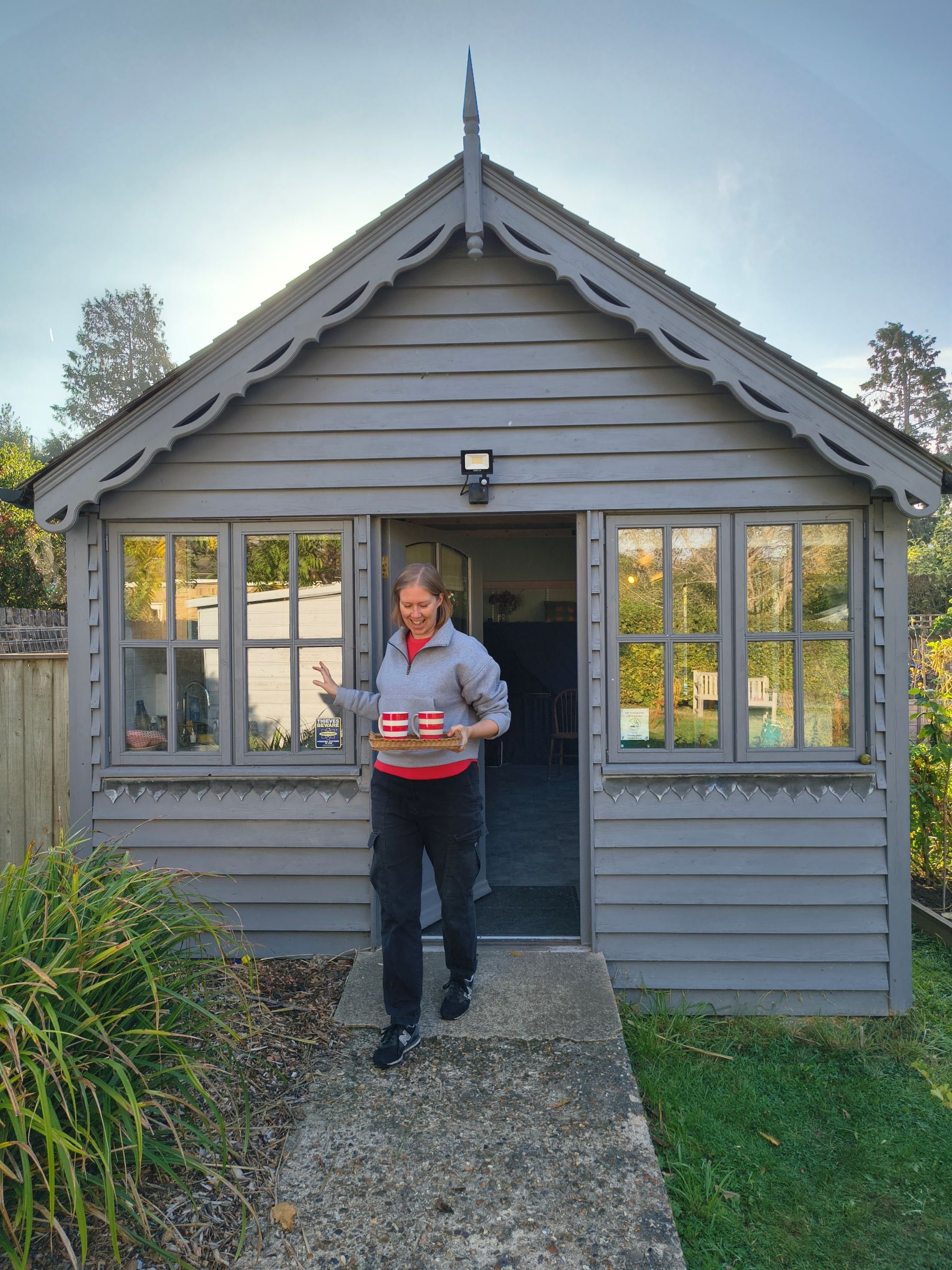 A person coming out of a Garden Room holding a tray of tea mugs