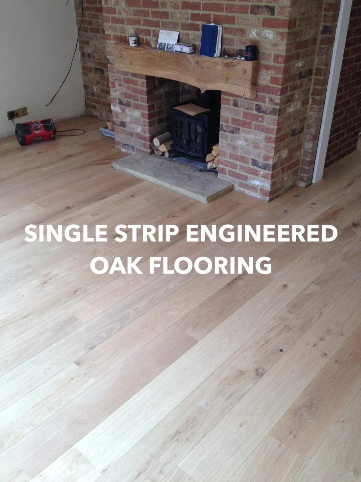 Single-strip engineered oak flooring beside a brick fireplace.