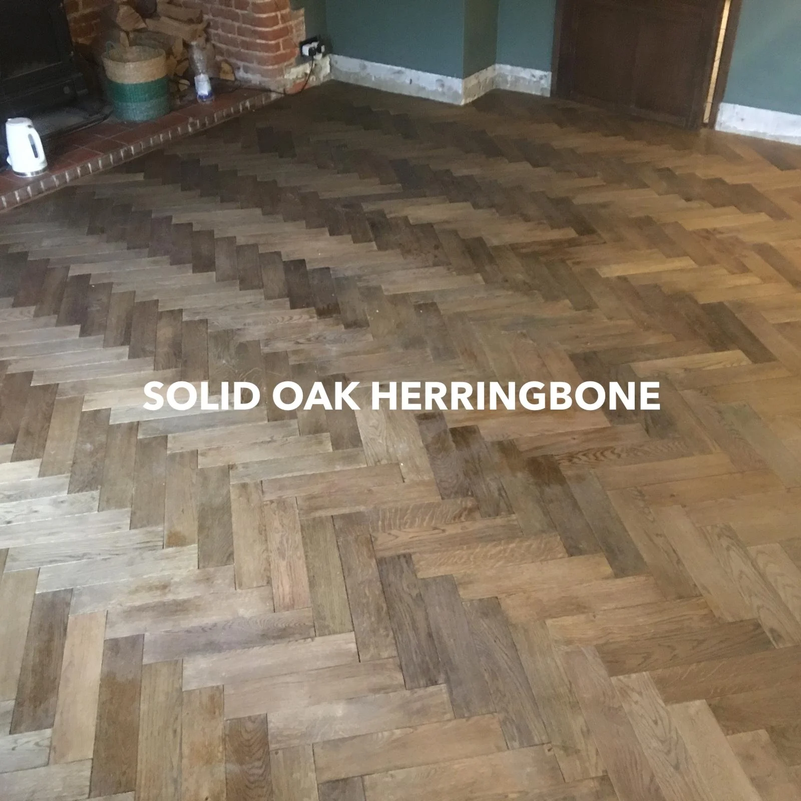 Solid oak herringbone flooring in a room with a brick fireplace.