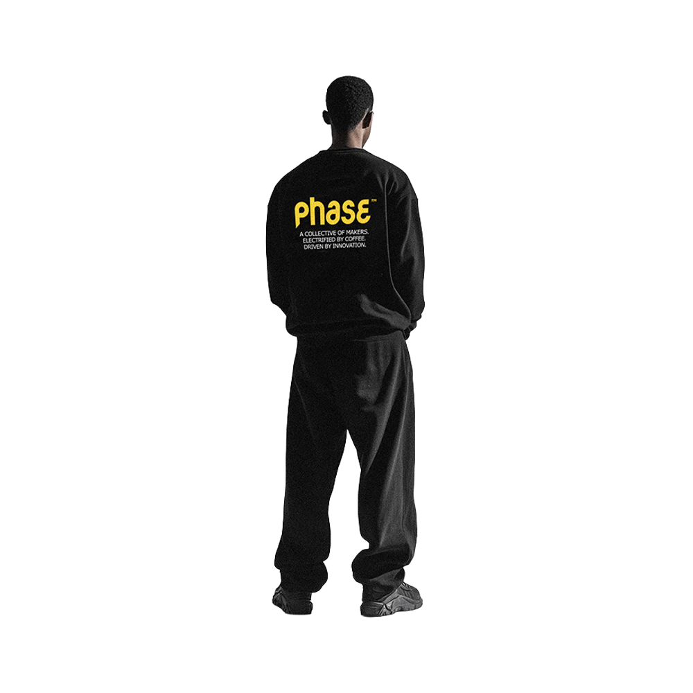 A black t-shirt with yellow and white graphic design and text, placed on a gray textured surface.