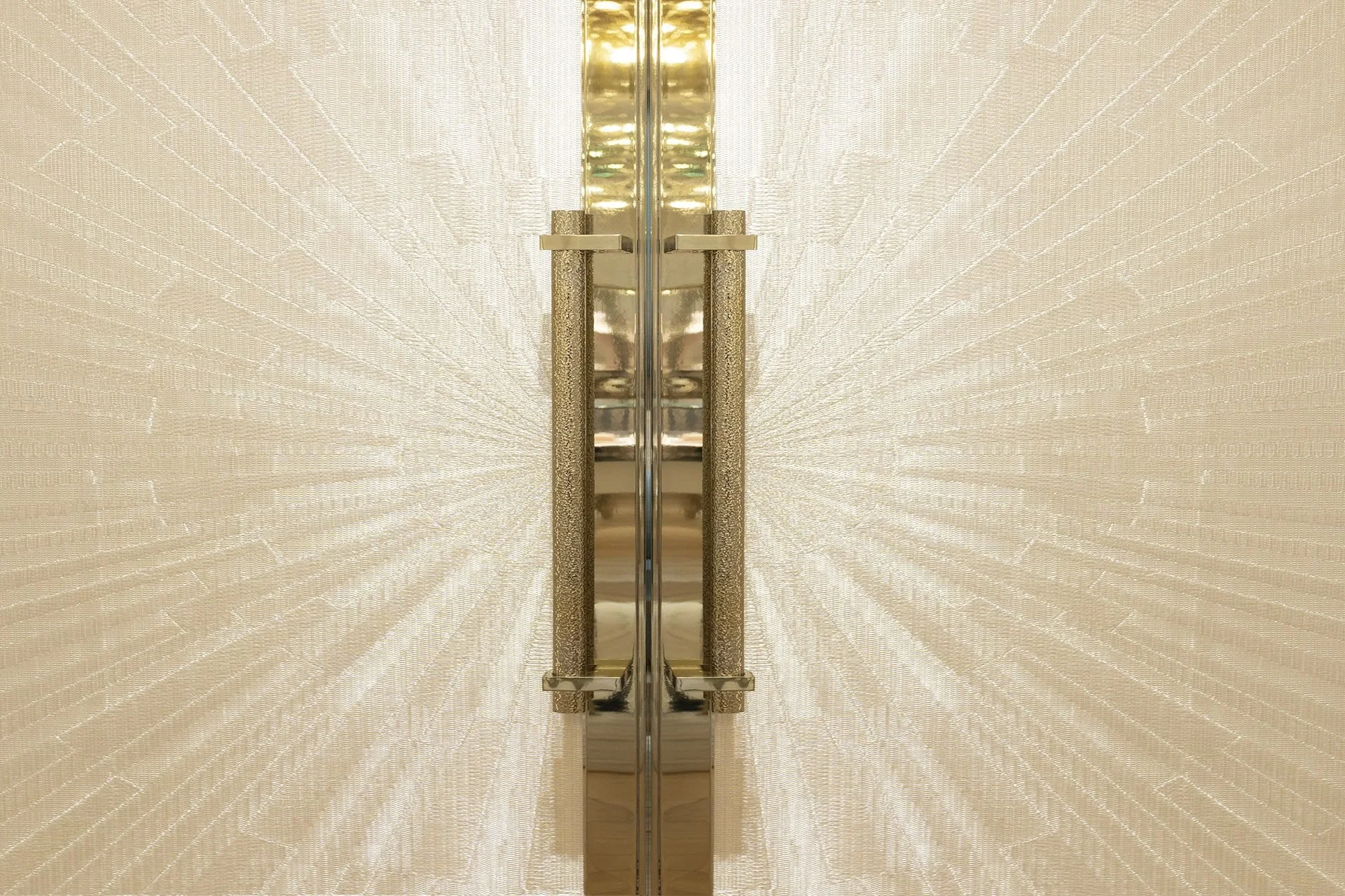 Close-up of a modern gold wall sconce with textured white fabric shades