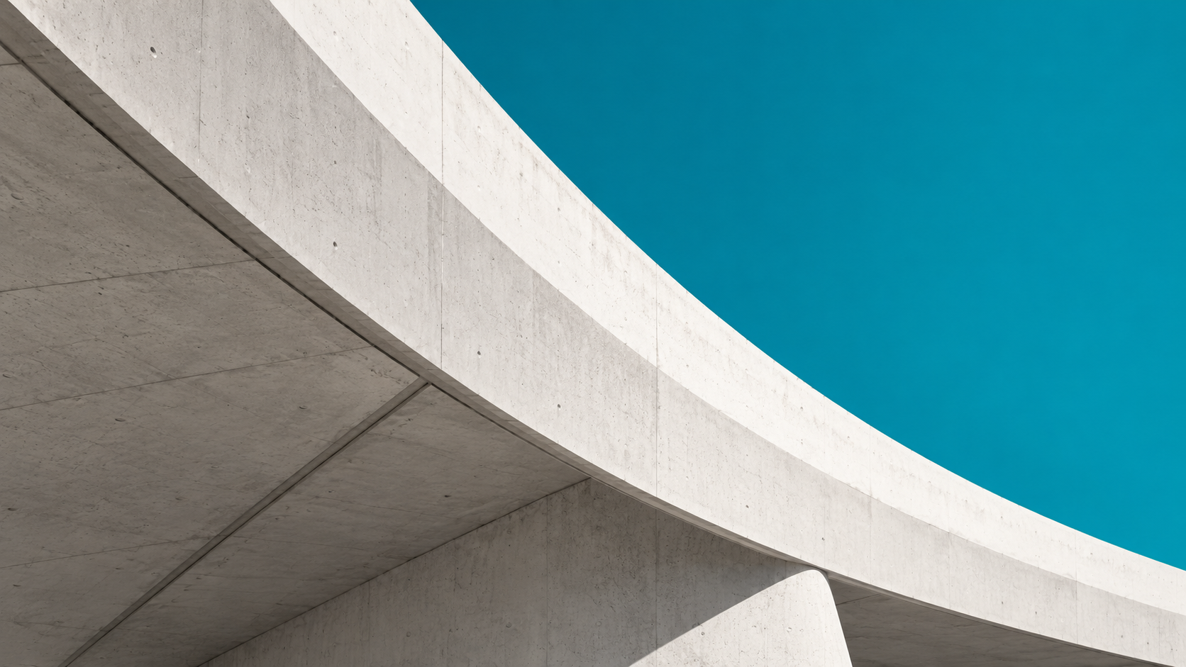 Sweeping concrete architecture against a teal sky.