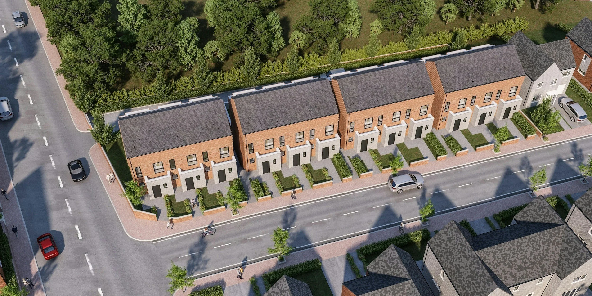 Aerial view of a row of modern townhouses with brick facades and small front yards, situated along a city street with cars and pedestrians, backed by a green park area.