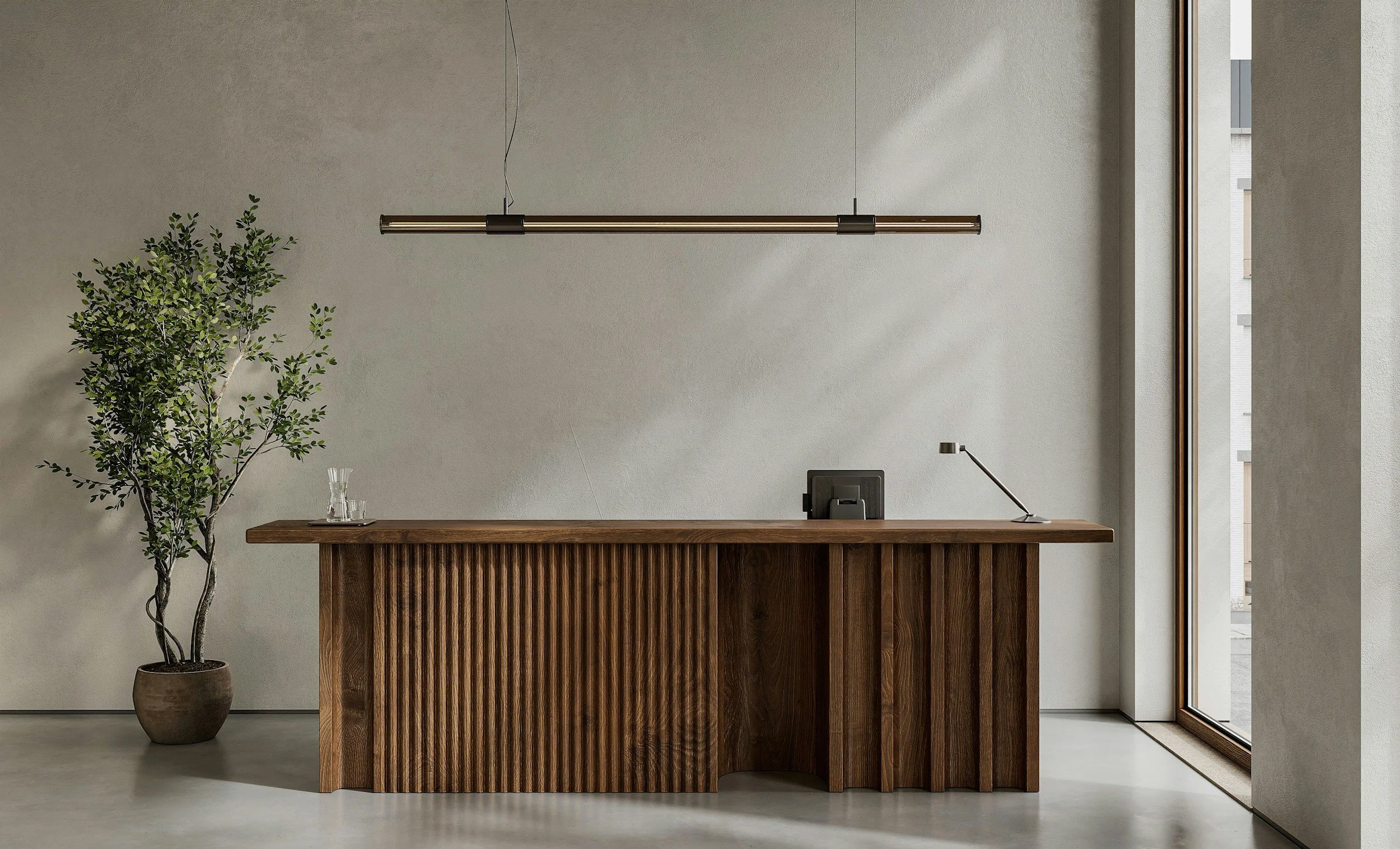 Modern office reception desk with a large potted plant on the left and a window on the right side.