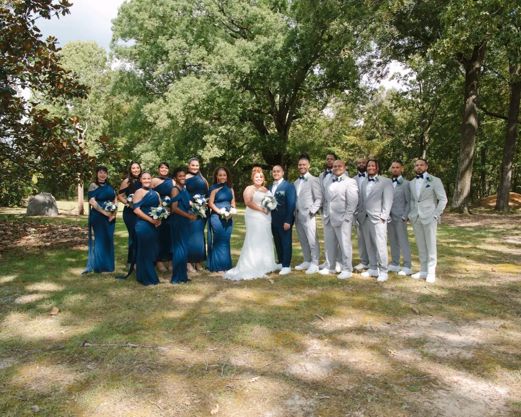 Wedding party group portrait outdoors under the trees