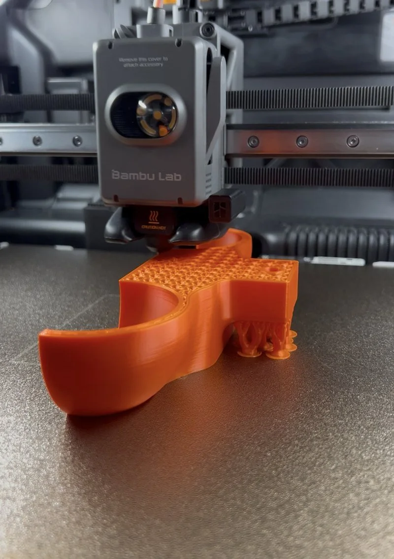 Orange PETG rocker foot printing on a Bambu Lab printer