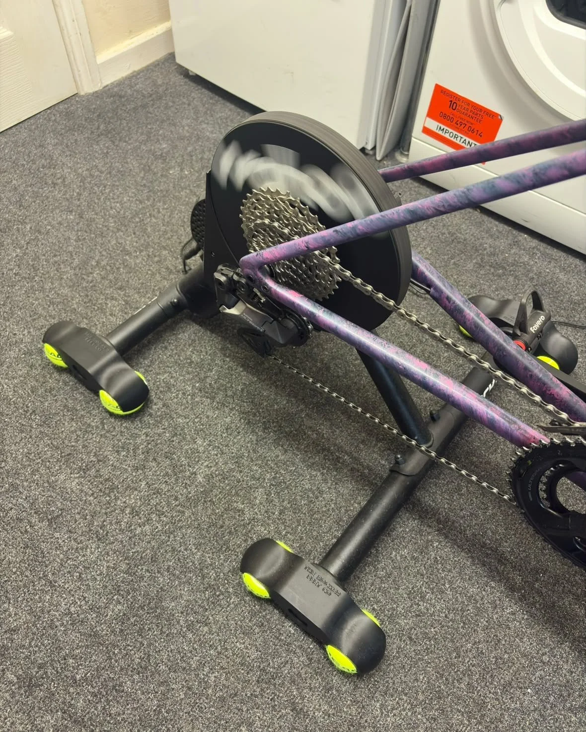 Wahoo KICKR CORE on black rocker feet with tennis balls in a rider's pain cave