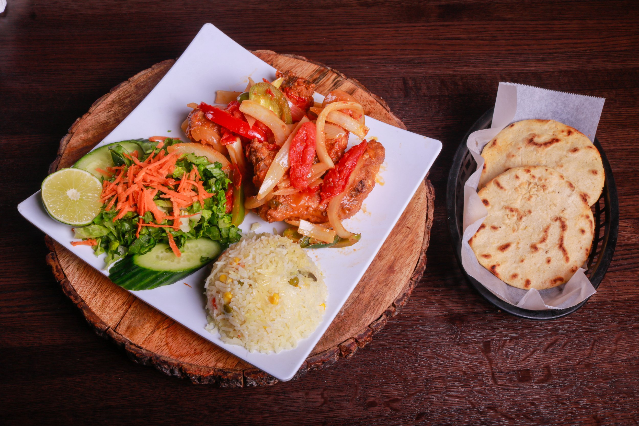 Latin American platter with grilled chicken, sautéed peppers and onions, rice, salad, lime, and flatbread