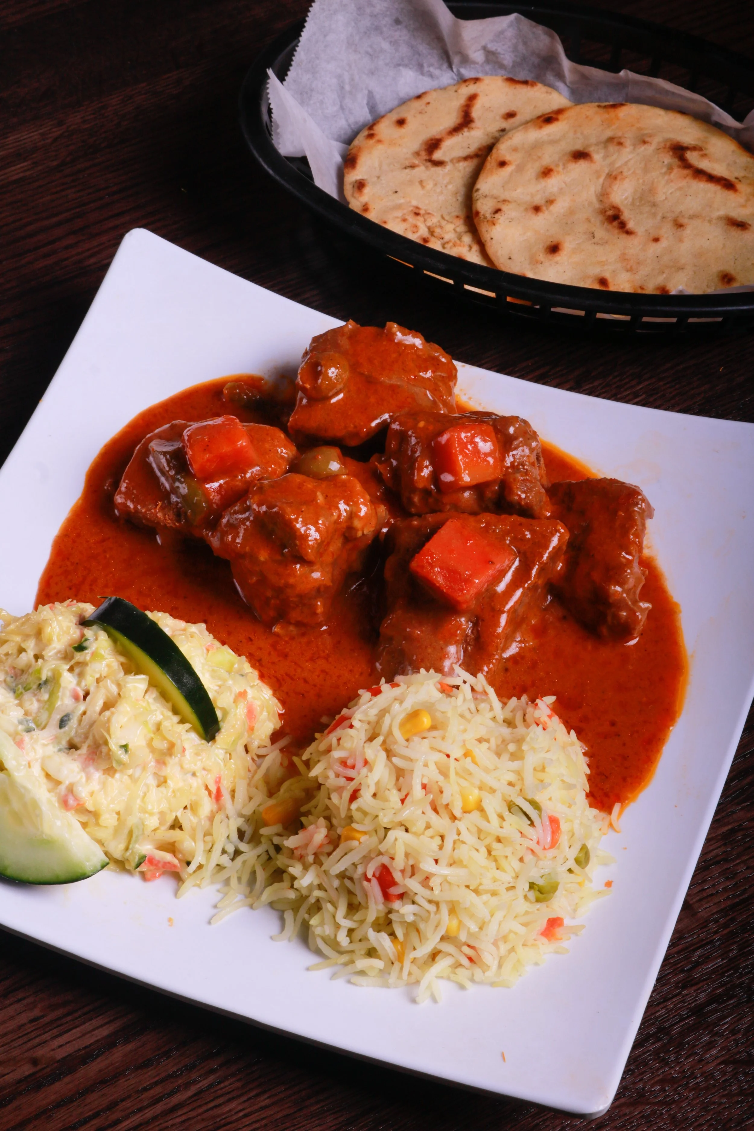 Plate of chicken tikka masala with basmati rice, creamy coleslaw, and naan bread