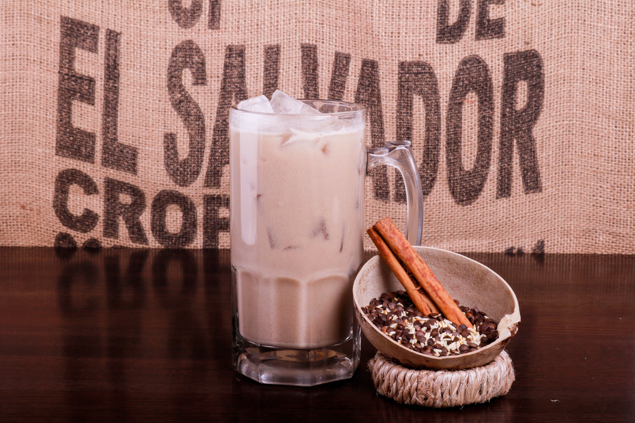 Iced horchata in a glass mug with cinnamon sticks and rice garnish on a wooden table