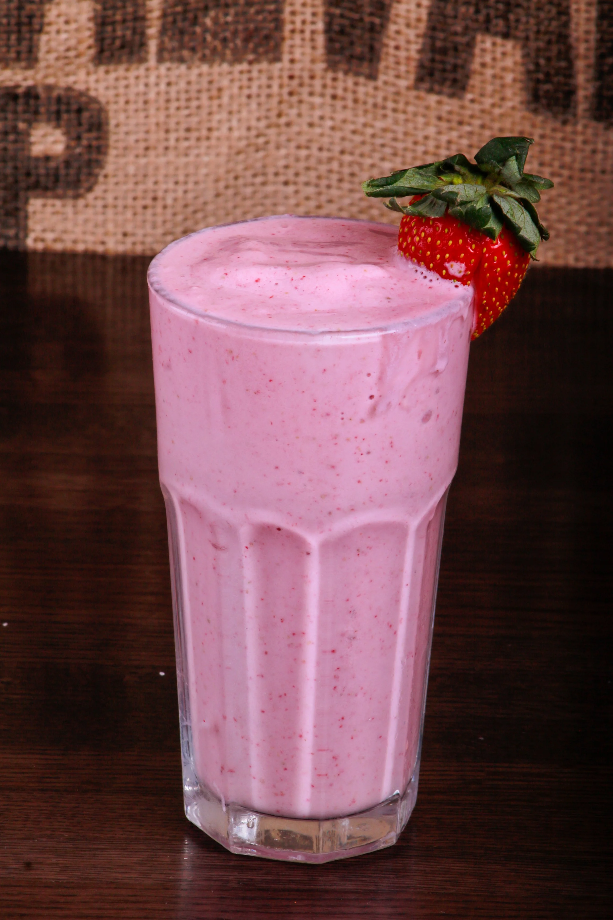 Pink strawberry smoothie in a glass topped with fresh strawberries