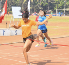 Two girls running on a track during a race, with one girl crossing the finish line.
