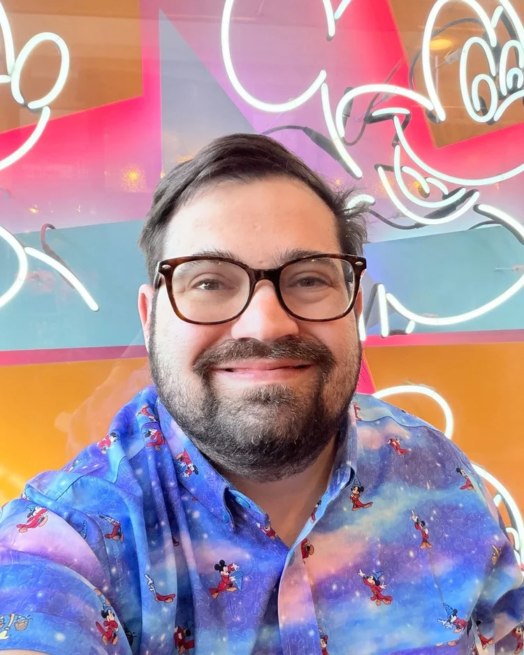 Josh Richter smiling in front of neon Mickey Mouse artwork