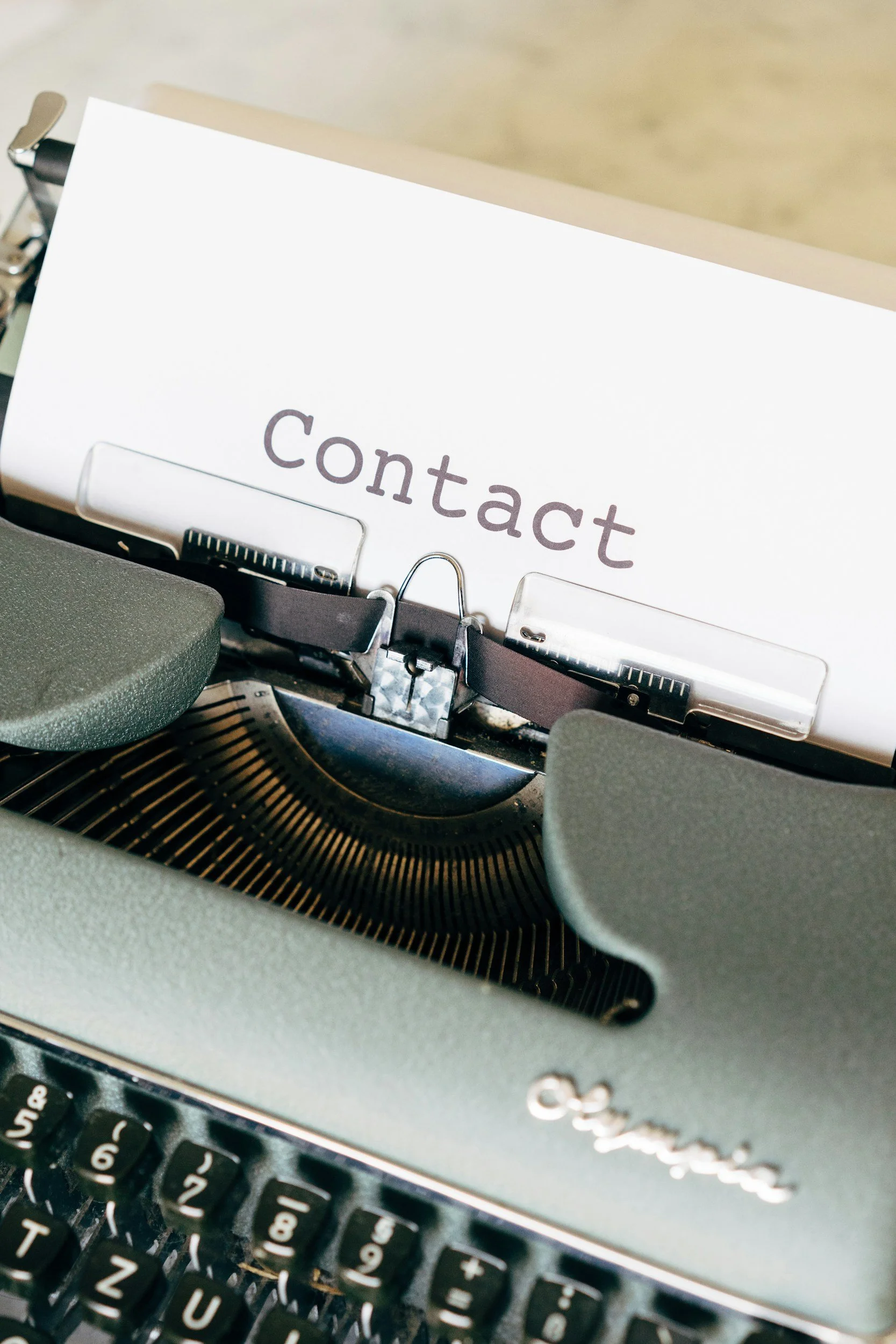Close-up of a vintage typewriter with a sheet of paper labeled “Contact.”