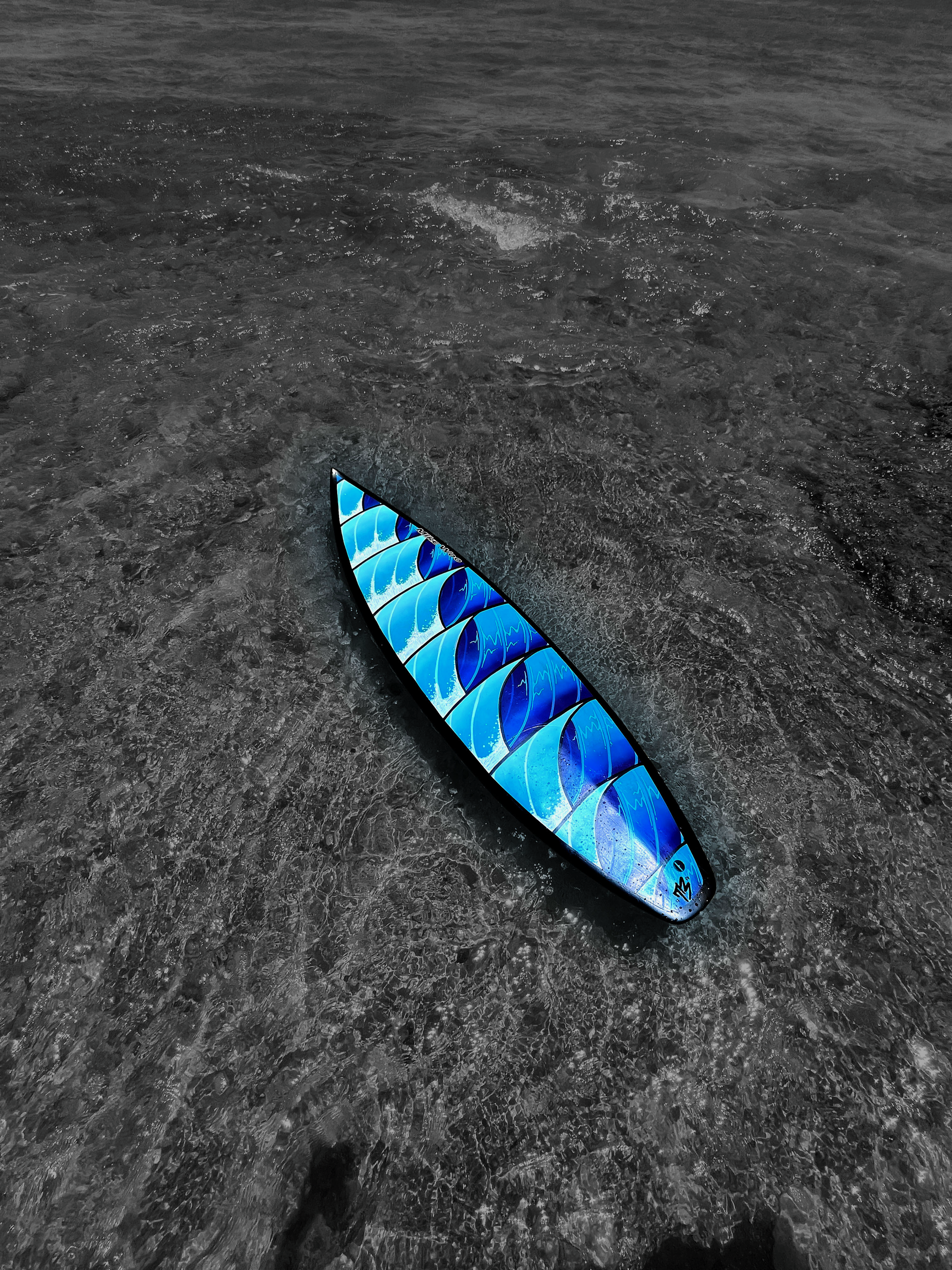 Blue patterned paddleboard floating in shallow ocean water