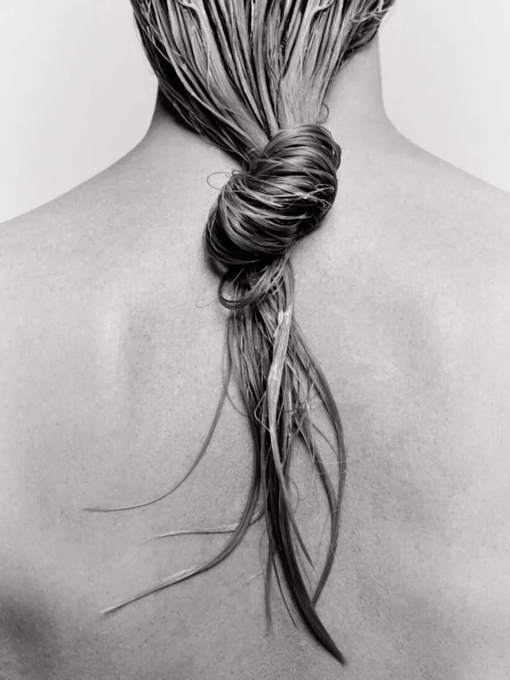 Close-up of a person's back with wet hair styled in a loose twisted braid.