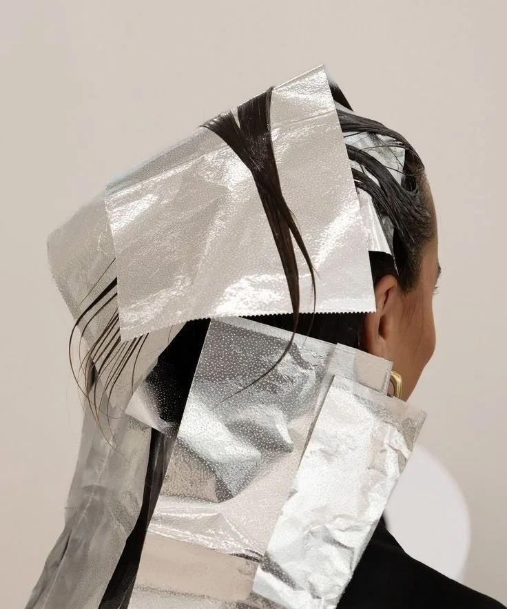 A woman having her hair done with foil highlights in a salon.