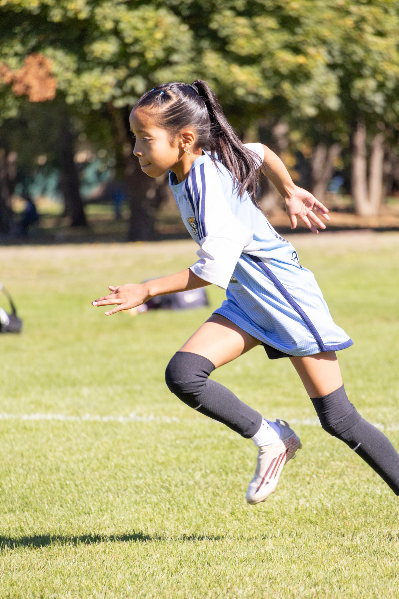 Young girl playing soccer outdoors on a sunny day.
