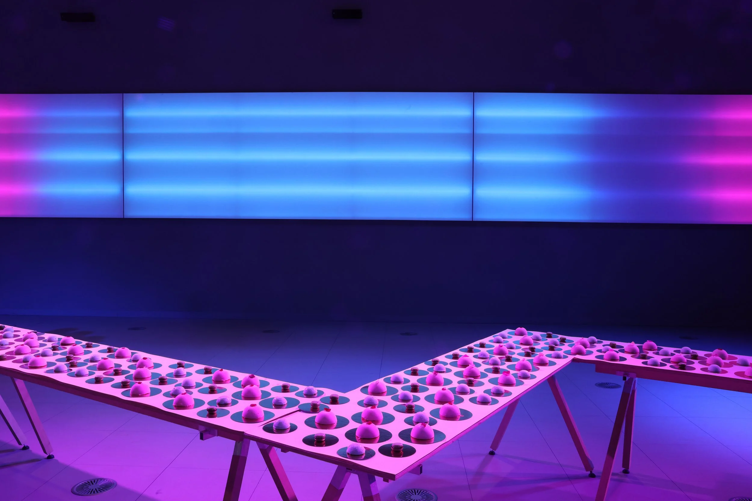 Tablero de sopa de bolas y pequeñas bolas en un entorno con iluminación rosa y azul.