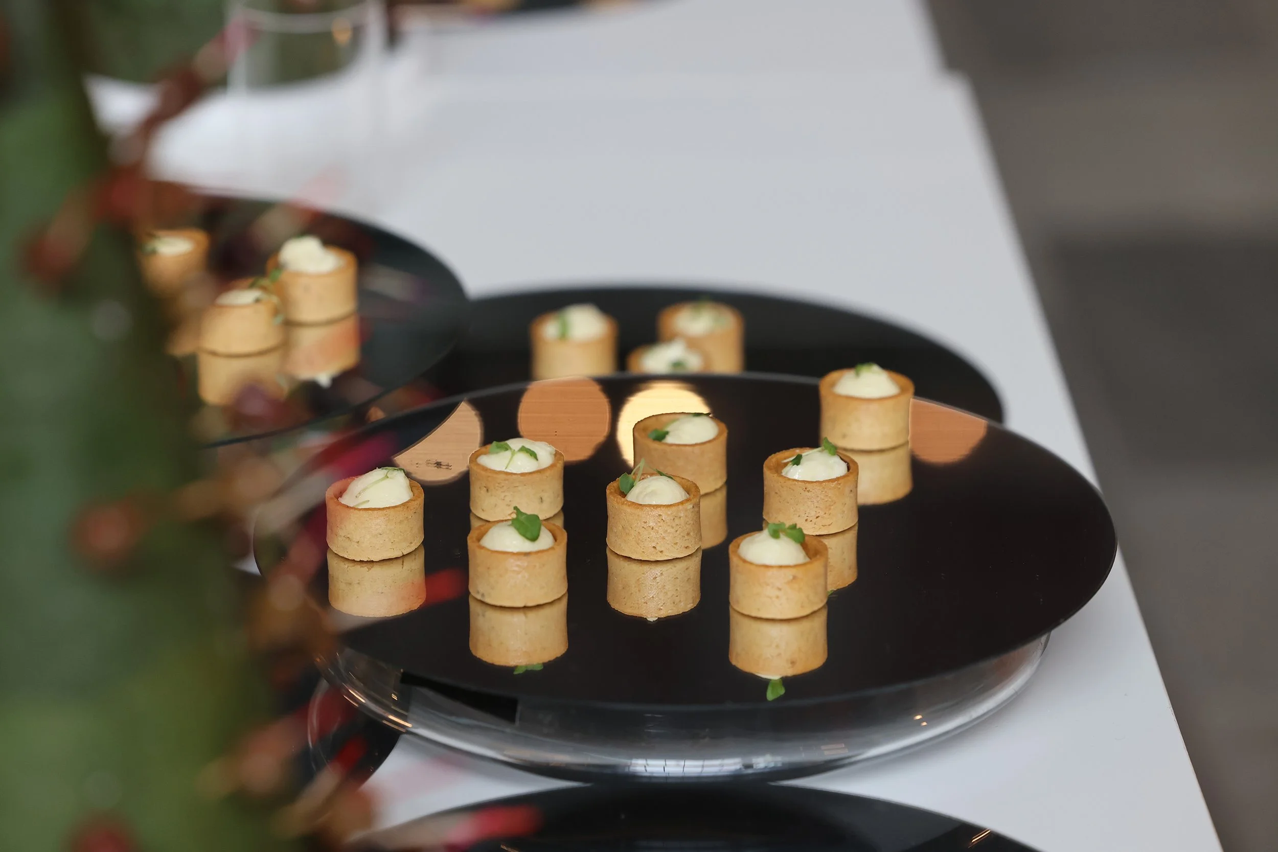 Variedad de canapés con crema y hierbas sobre un plato negro.