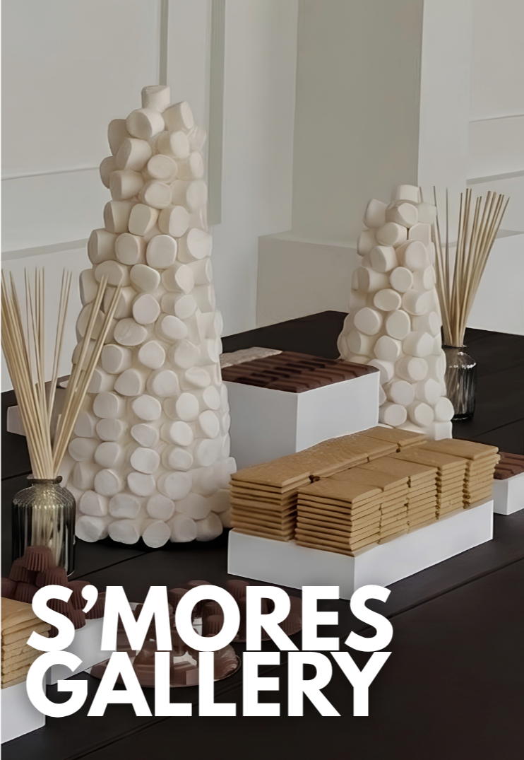 Decoración con cilindros blancos apilados, palitos de madera en frascos y galletas en platos en una mesa negra.