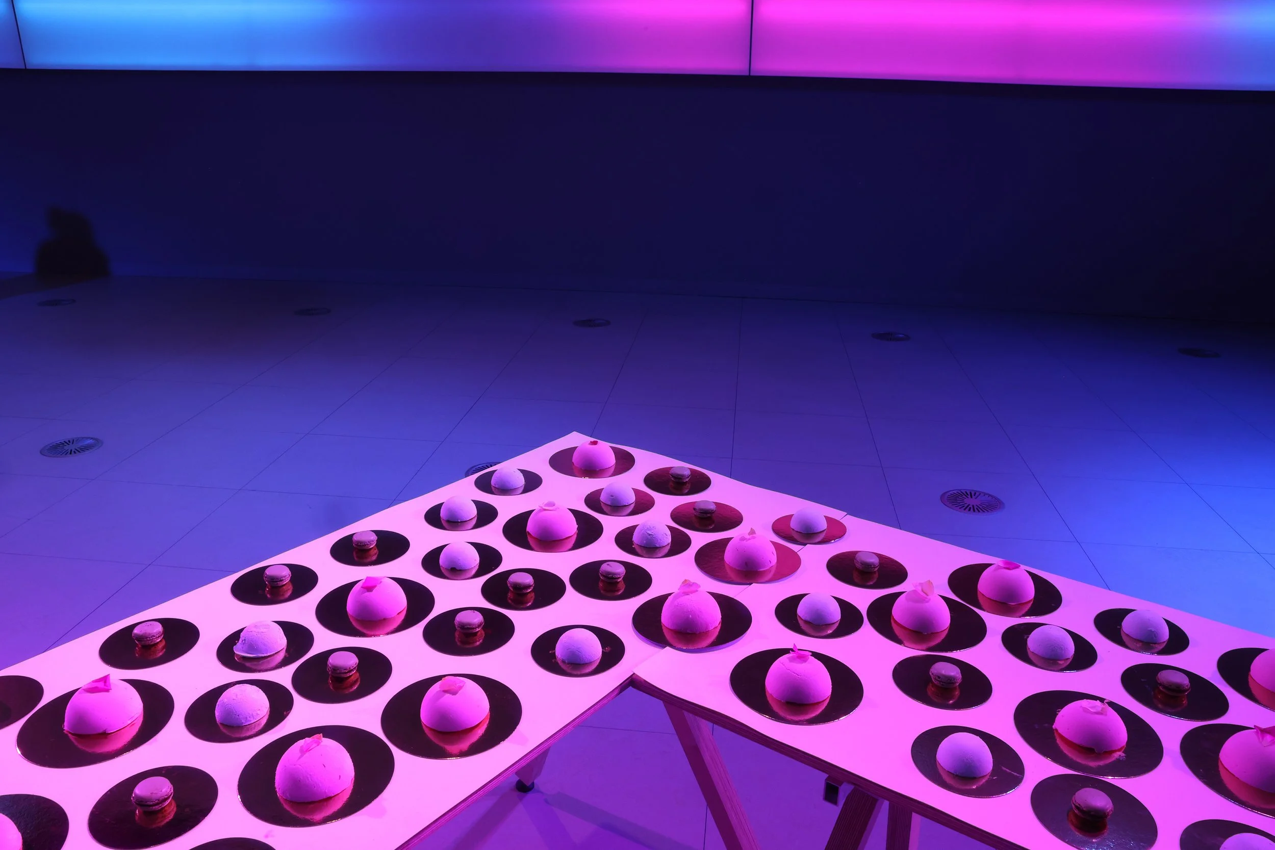 Mesa blanca con varias galletas en círculos negros en un entorno con iluminación púrpura y azul.