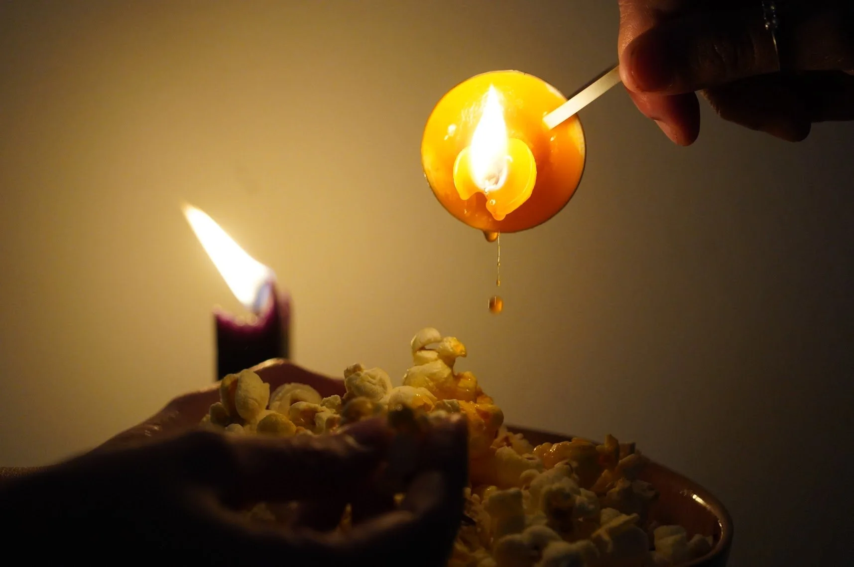 Una vela de mantequilla encendida con palomitas de maíz en primer plano.