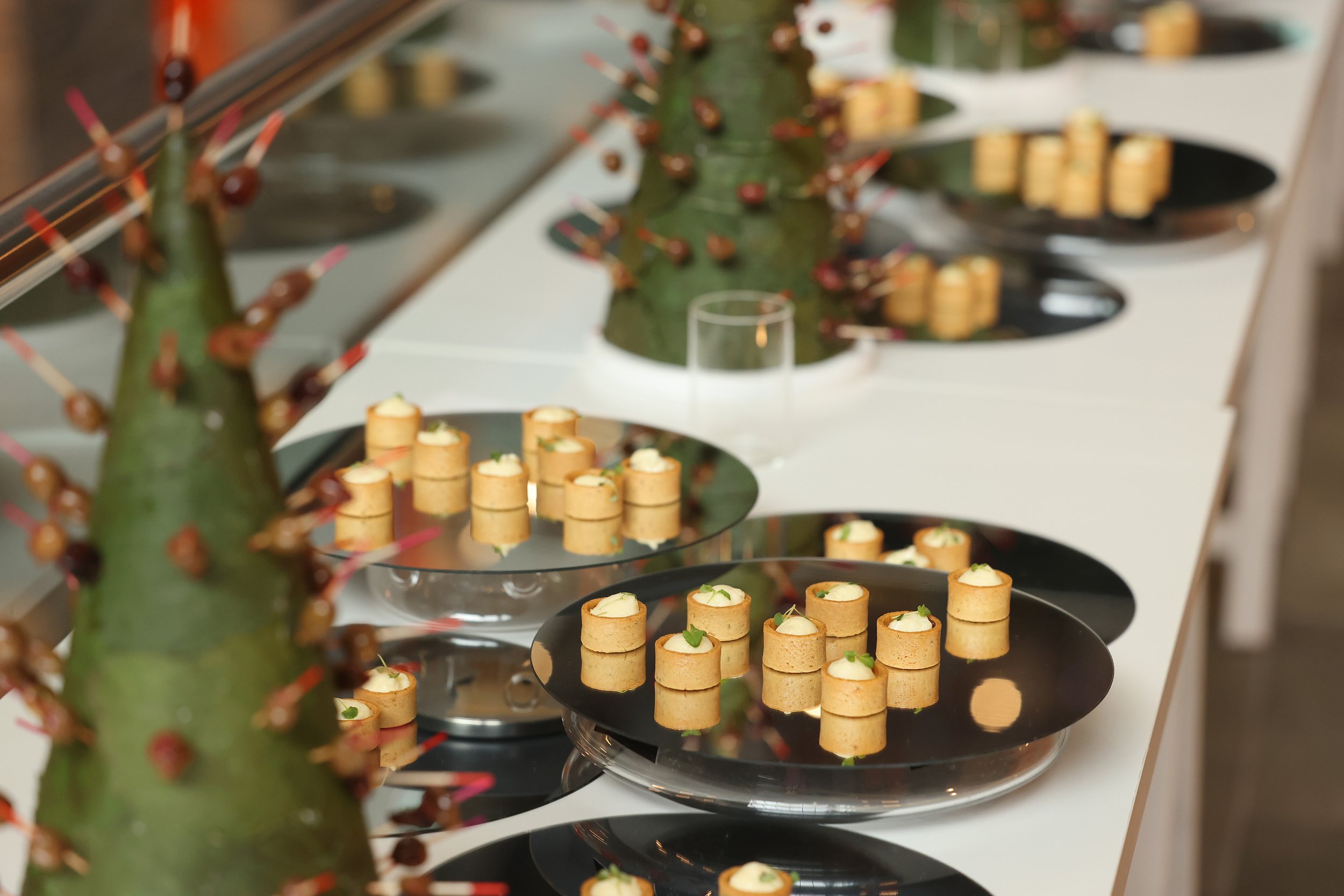 Varios aperitivos en copas y platos en una presentación elegante en una mesa, con un cactus decorativo en primer plano.