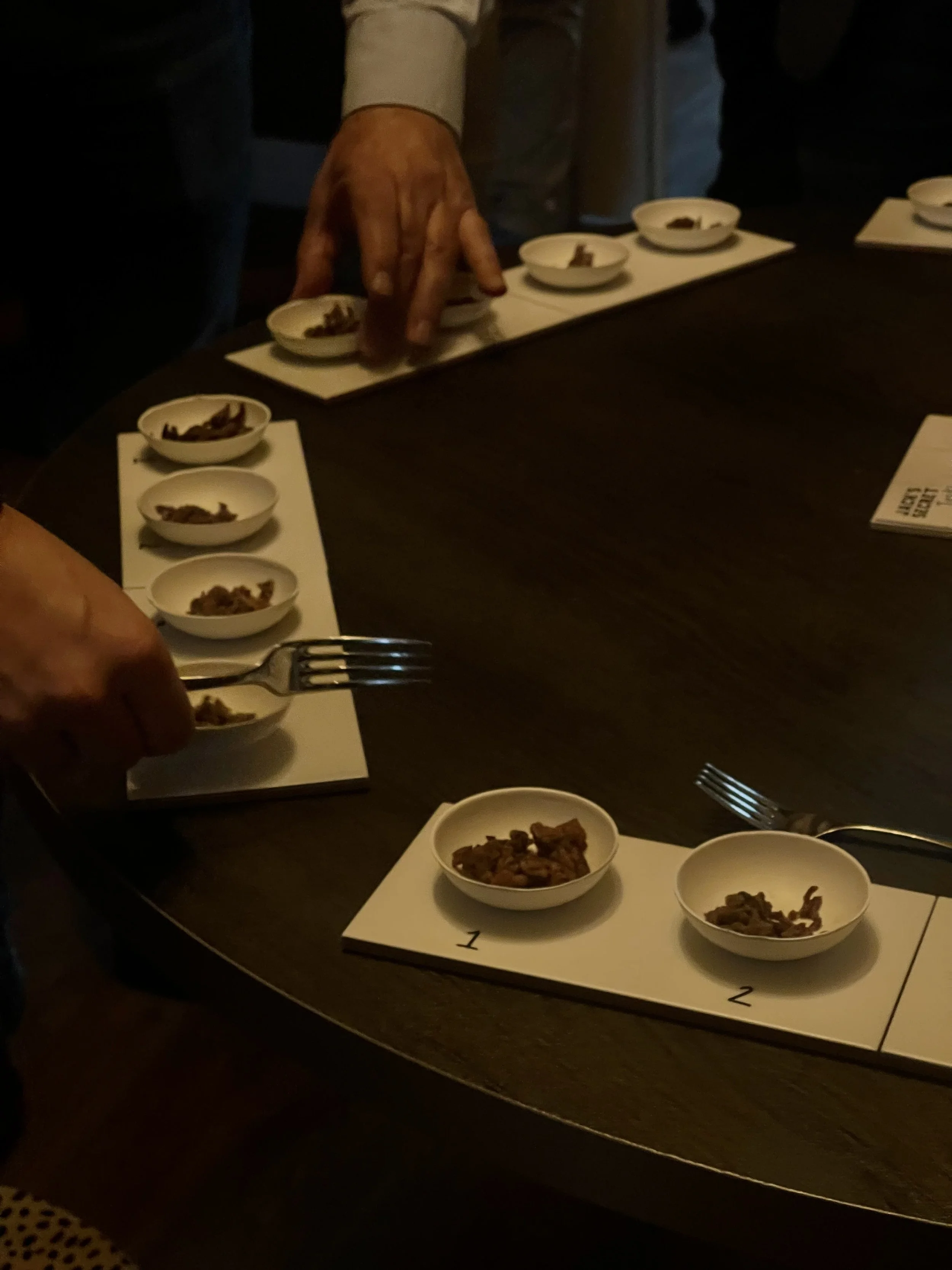Una persona sirviendo diferentes tipos de comida en pequeñas tazuelas en una mesa.