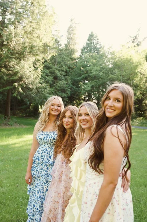 Friends in pastel dresses gathered together in a garden during Caitlyn Deming’s branding photoshoot.