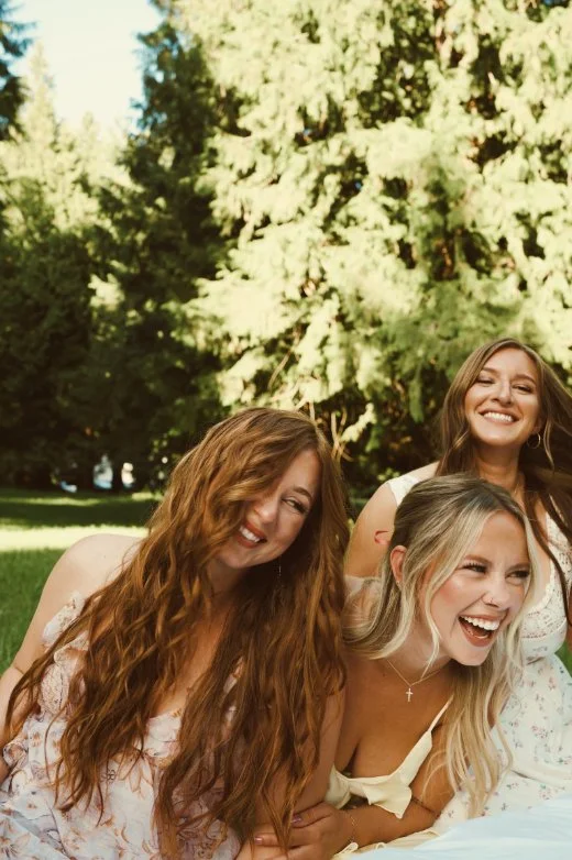 Friends in pastel dresses gathered together in a garden during Caitlyn Deming’s branding photoshoot.