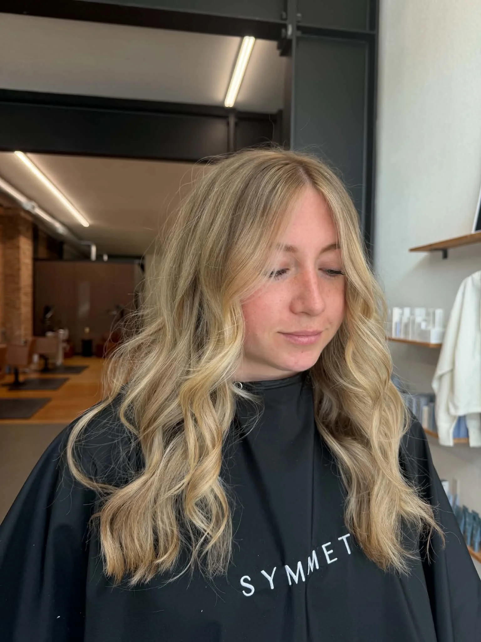 Woman with long blonde hair and soft dimensional color styled by Caitlyn Deming.
