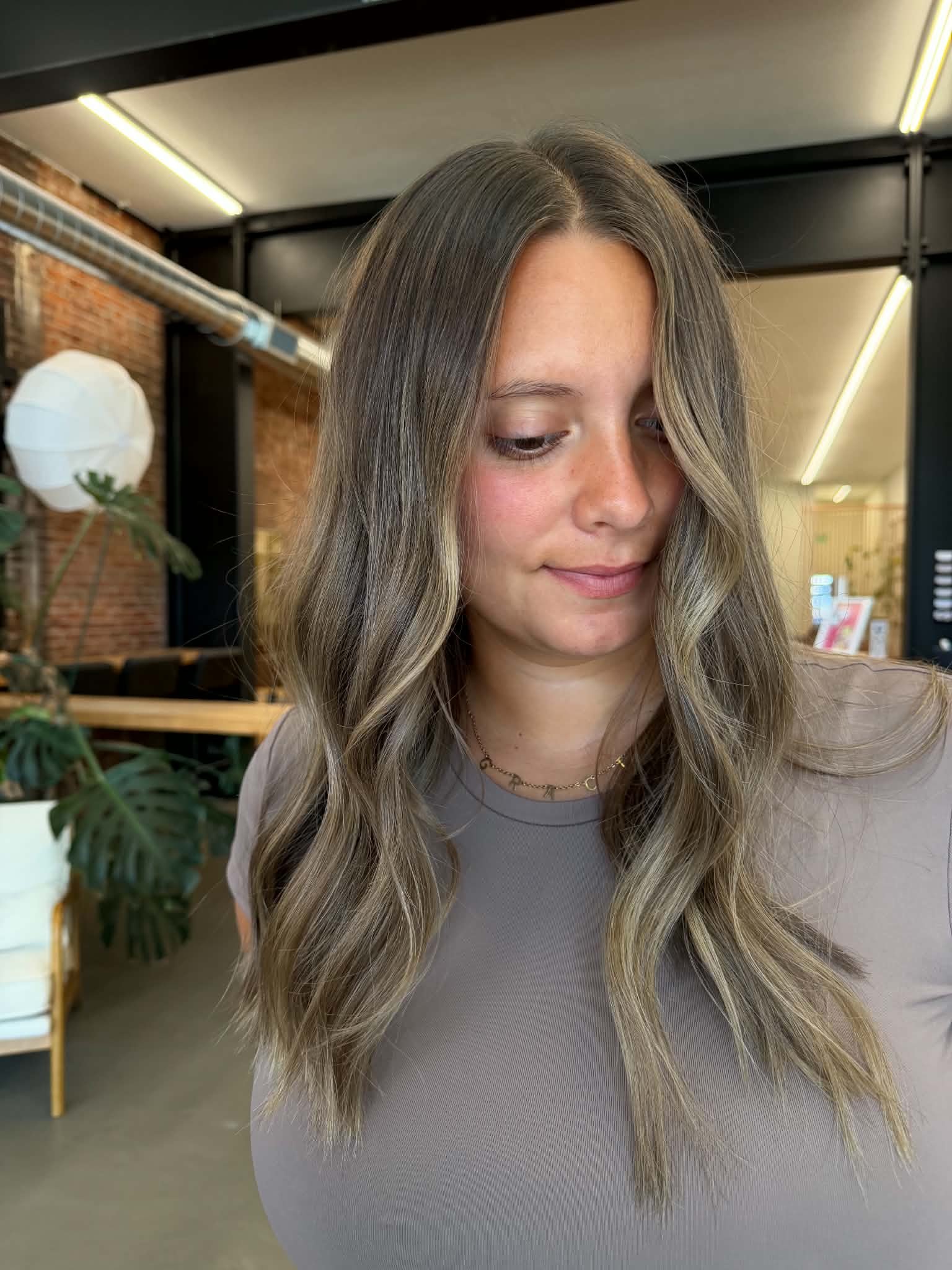 Woman with shoulder-length brunette waves and dimensional color by Caitlyn Deming.