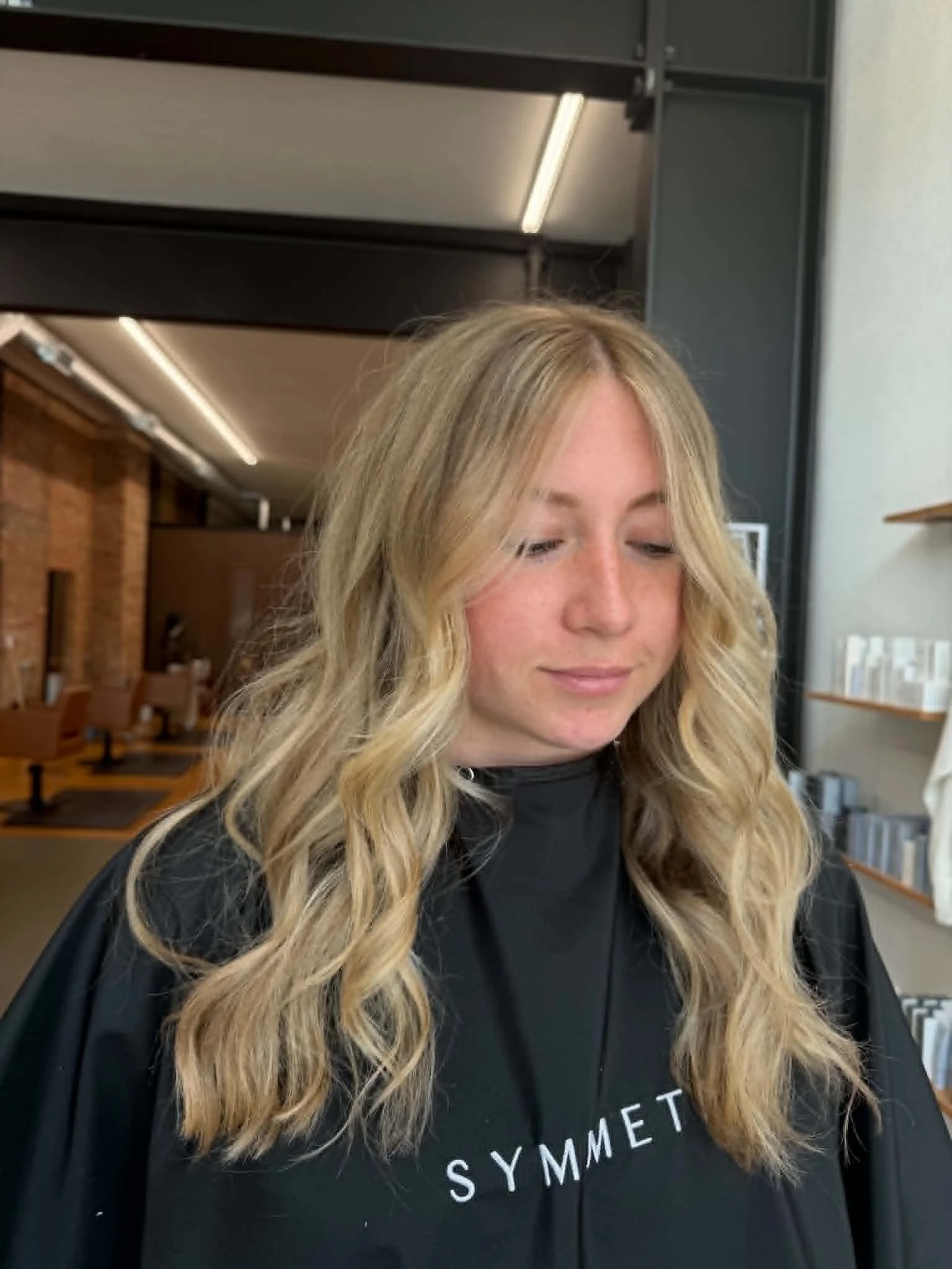 Woman with long blonde hair and soft dimensional color styled by Caitlyn Deming.