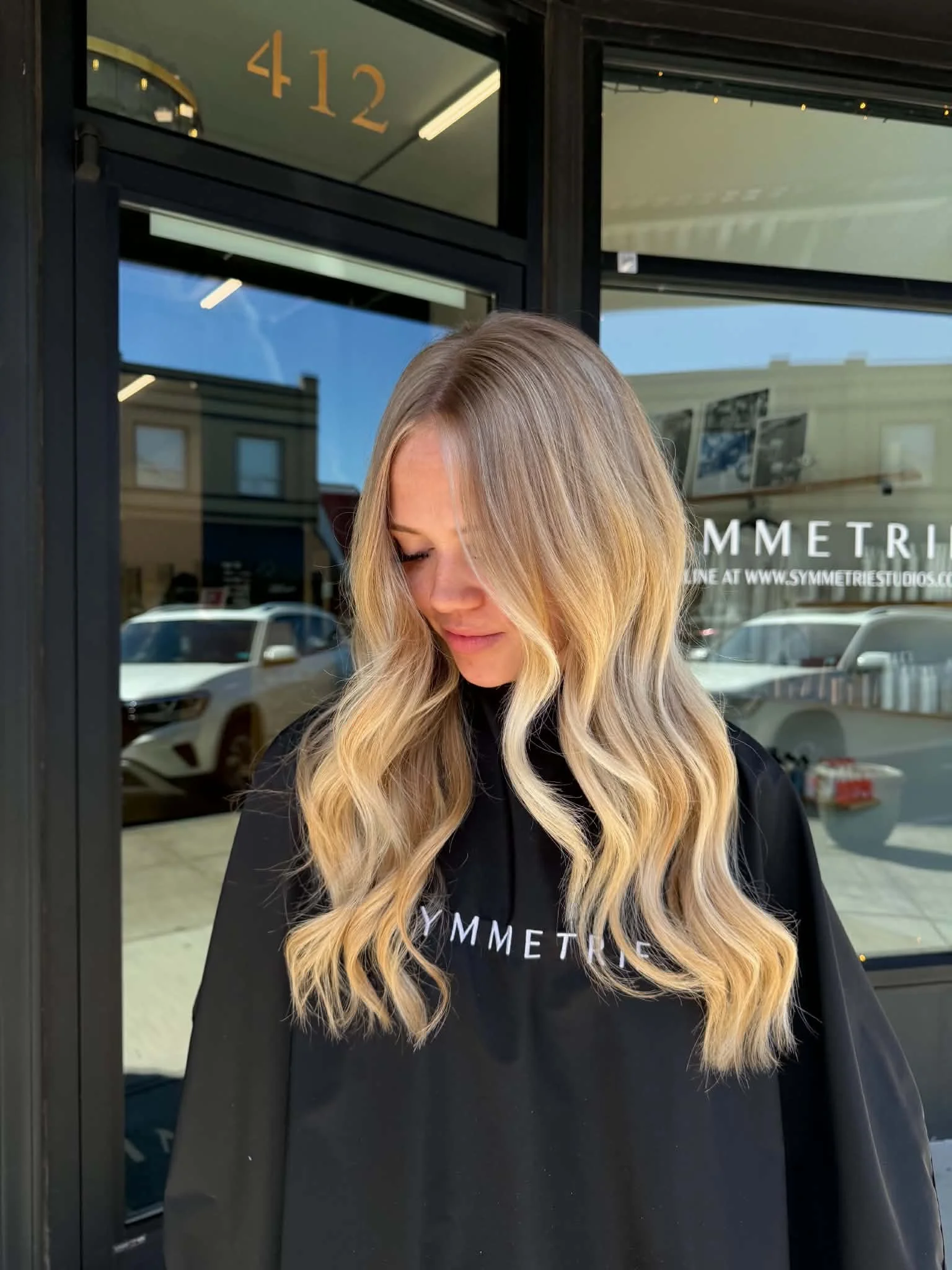 Long warm blonde hair with blended highlights and loose waves by Caitlyn Deming.
