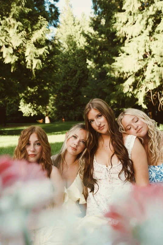 Friends in pastel dresses gathered together in a garden during Caitlyn Deming’s branding photoshoot.