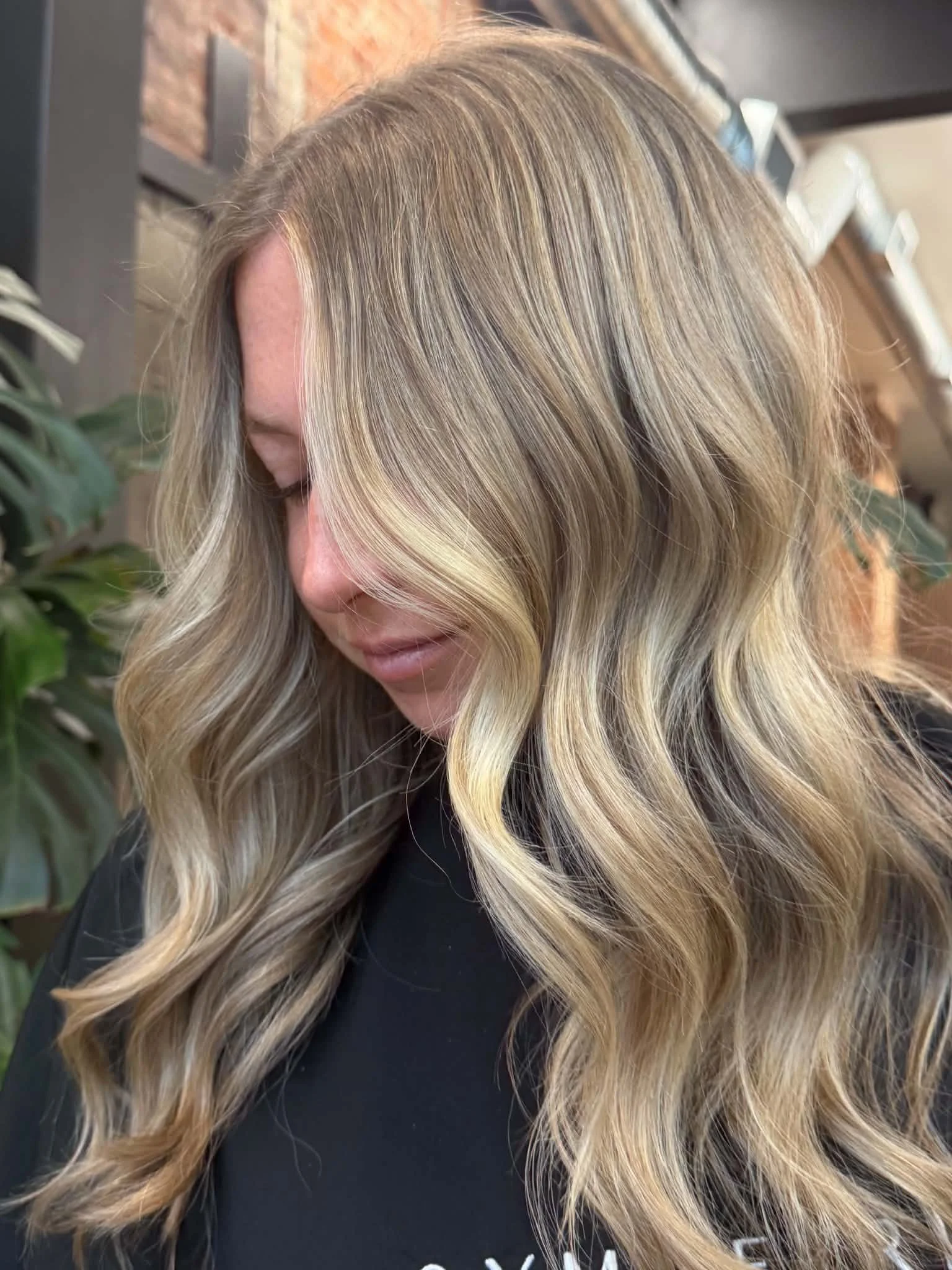 Long dimensional blonde hair with soft face-framing layers and loose waves by Caitlyn Deming.