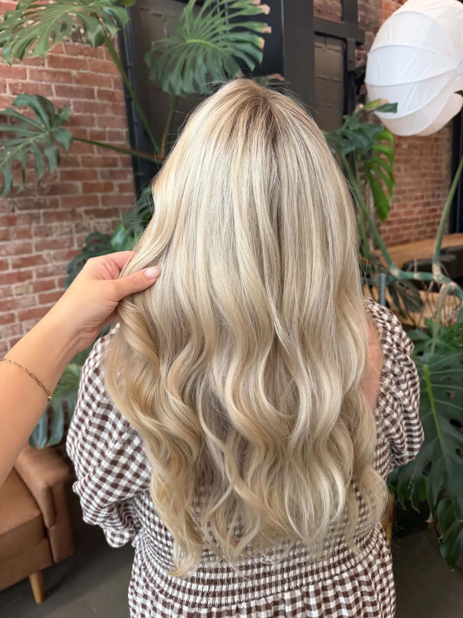 Back view of long creamy blonde balayage with soft, blended dimension by Caitlyn Deming.