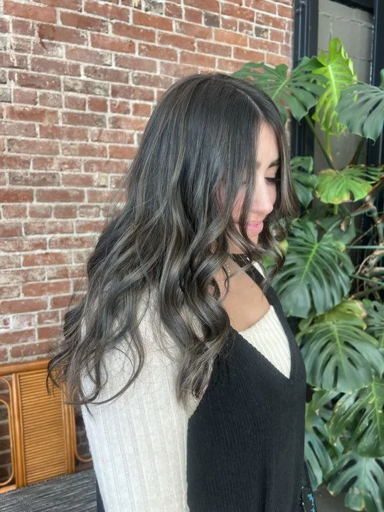 Woman with long brunette hair and soft dimensional color styled by Caitlyn Deming.