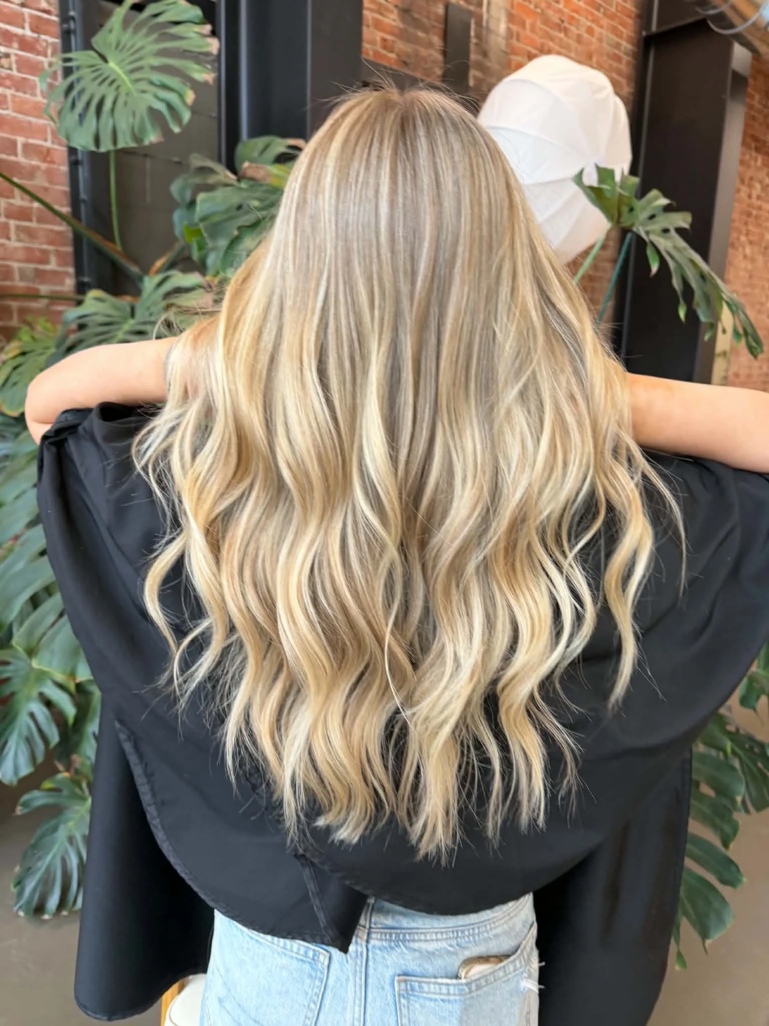 Woman with long, softly waved blonde hair styled by Caitlyn Deming.