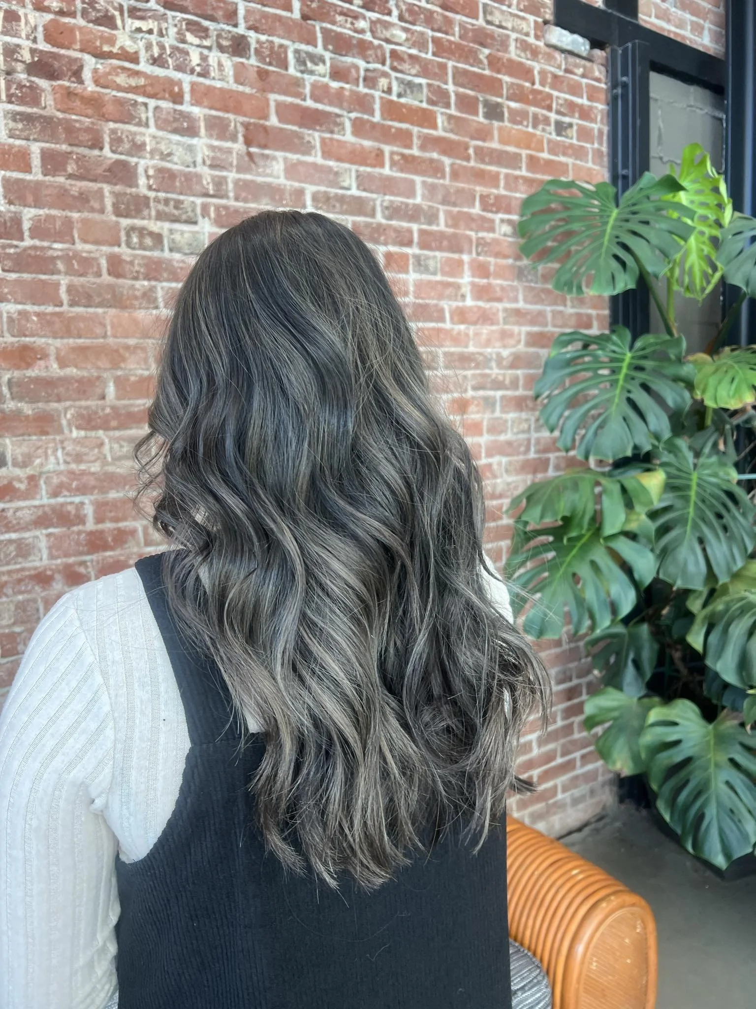 Woman with long brunette hair and soft dimensional color styled by Caitlyn Deming.