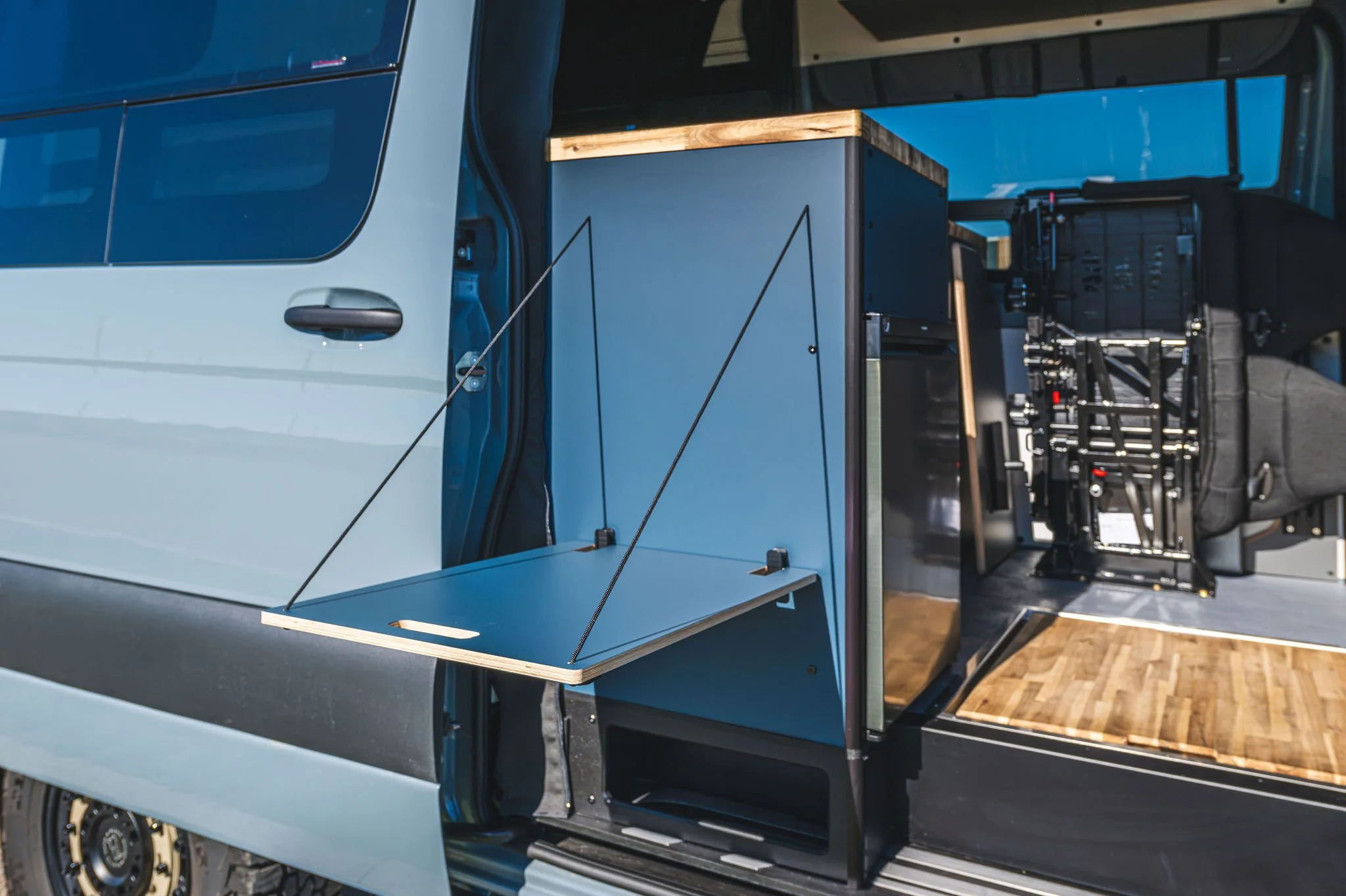Aménagement intérieur du fourgon d'aventure Hervé G2 avec espace de rangement modulable et mobilier en bois.